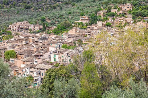 View at an old idyllic village on a mountainside with houses and lush green trees, Sóller,