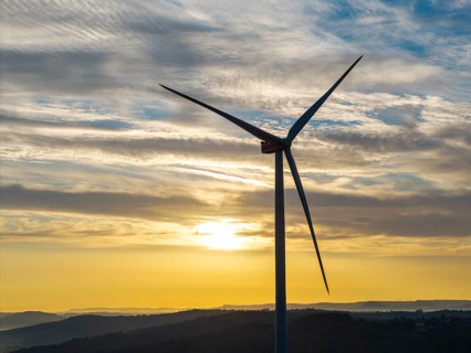 A single wind turbine stands majestically against a breathtaking sky at sunrise, near Schorndorf,