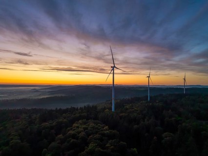 Three wind turbines on a green hill at sunrise with sweeping mountain views, near Schorndorf,