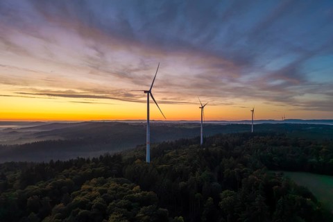 Three wind turbines on a wooded hill with a dramatic sunrise sky, near Schorndorf, Remstal,