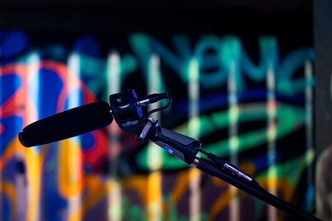 A microphone in the foreground against a colourfully lit graffiti background in a studio, London,