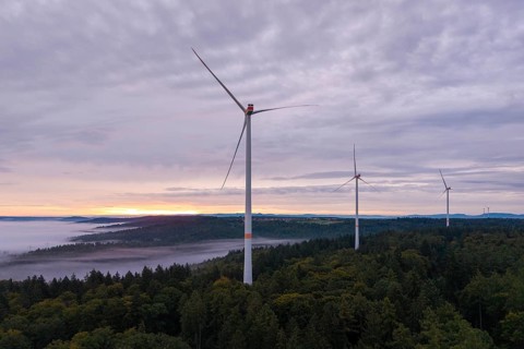 Three wind turbines above a forest at dusk under a cloudy sky, near Schorndorf, Rems-Murr district,