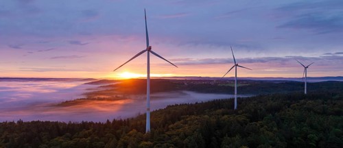 Powerful wind turbines over a misty forest and a wide horizon at sunrise, near Schorndorf,