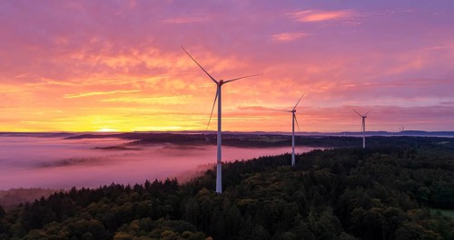 Wind turbines above a forest in front of sunrise with dramatic cloud formation, near Schorndorf,