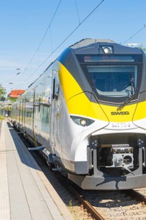 Modern white and yellow train on the track in sunny weather, taken from the side, battery Electric