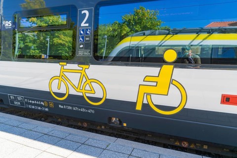Train with bicycle and wheelchair symbols on a sunny platform surface, battery Electric train with