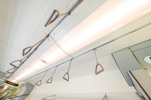 Modern ceiling lighting with grab rails in an interior, battery Electric train with green