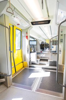 Modern entrance in the train with yellow doors and brightly lit interior, battery Electric train