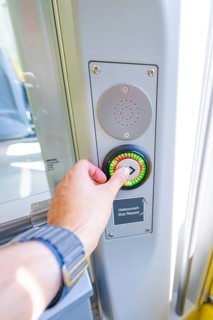 Hand presses stop button on a modern vehicle door, battery Electric train powered by green