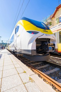 Yellow and white train on the tracks, slight angle of view from below at the station, battery