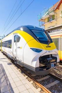Yellow and white modern train on a sunlit platform, battery Electric train with green electricity,