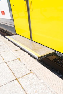 Close-up of a step on the yellow train belt line on the platform, battery Electric train with green