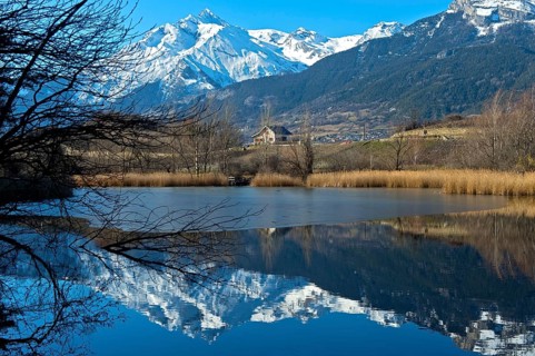The snow-covered Haut de Cry mountain range is reflected in the Mont d'Orge lake, Lac de Mont