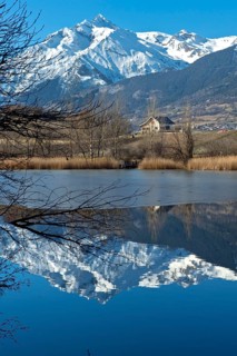 The snow-covered Haut de Cry mountain range is reflected in the Mont d'Orge lake, Lac de Mont