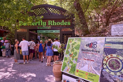 Entrance to a nature park full of butterflies with visitors and park sign, Butterfly Valley,