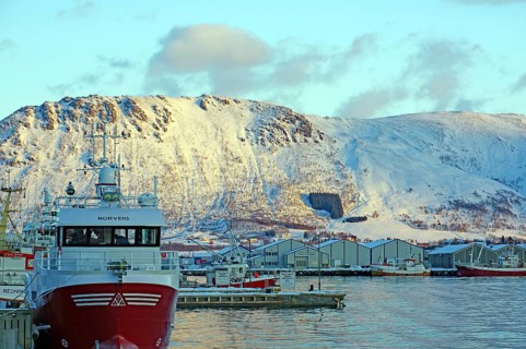 Norwegian harbour in front of snowy mountains in winter with boats and clouds in the sky, Myre,
