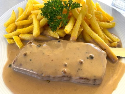 Portion of pepper steak, beef steak with pepper sauce, pepper sauce, French fries, on a plate,