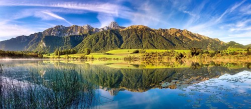 Stockhorn range with the Stockhorn mountain reflected in the Uebeschi lake in the morning light,