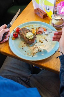 Person eating a steak with tomatoes and garnish on a blue plate, Lake Constance, Germany