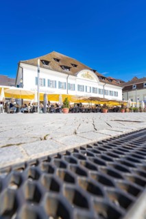 A café with yellow parasols in a cobbled street under a blue sky, Lake Constance, Germany