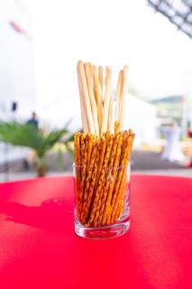 A glass container with breadsticks stands on a red table in an outdoor event area, Lake Constance,