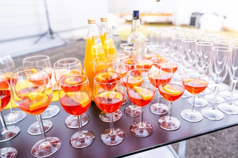 Many cocktail glasses with orange-coloured drink on a table at an outdoor party, Lake Constance,