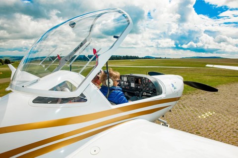 Pilot and passenger co-pilot preparing for take-off in cockpit of two-seater touring motor glider