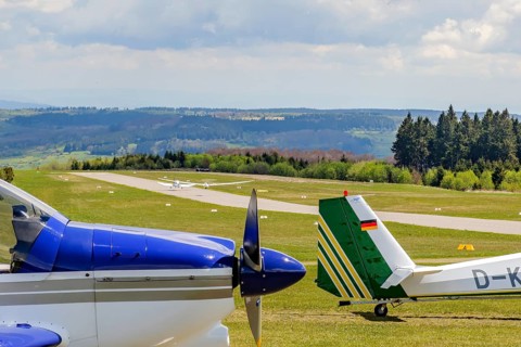 In the background runway and landing strip on it tow launching motorised aircraft towing glider