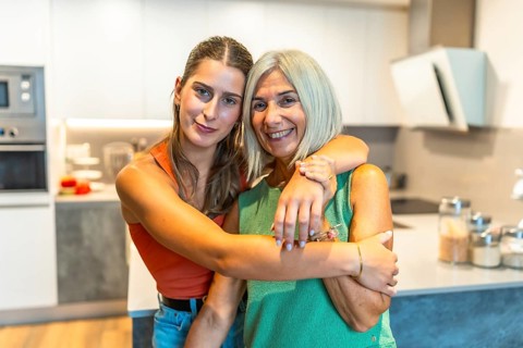 Young woman hugging her smiling mother in a bright modern kitchen, showing their loving bond and