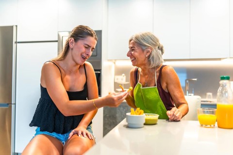 Grandmother and granddaughter laughing together while having a snack of french fries and guacamole