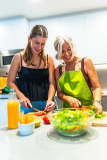 Smiling mother and daughter preparing a fresh salad together in a modern kitchen, highlighting
