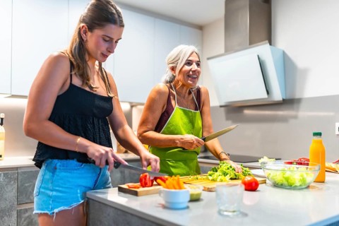 Two women enjoying a cooking session together, preparing fresh vegetables in a bright, modern