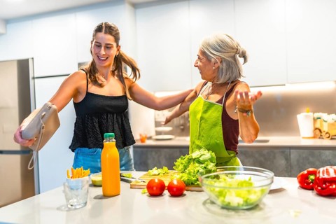 Joyful grandmother and granddaughter preparing a healthy meal in a bright, modern kitchen,