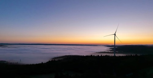 Single wind turbine above a sea of fog against a colourful morning sky, near Schorndorf, Remstal,