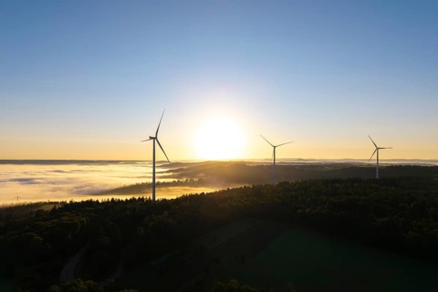 Three wind turbines in the soft morning light over a misty forest landscape, near Schorndorf,
