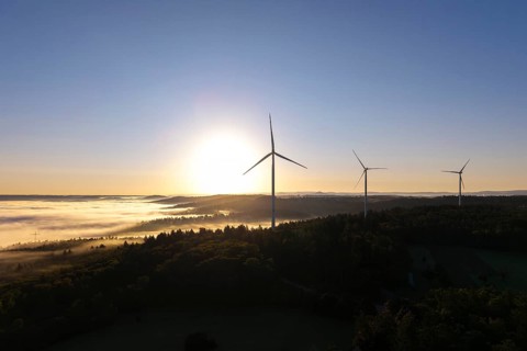 A wind turbine stands prominently in the morning fog under a clear sky, near Schorndorf, Remstal,