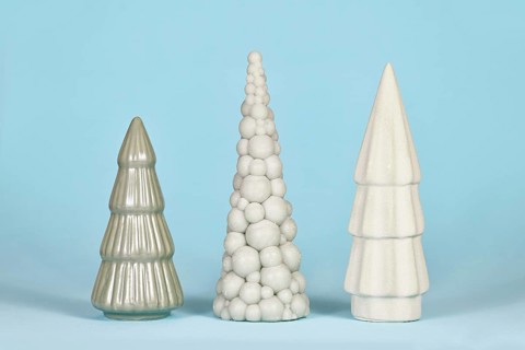 Three different shaped light green ceramic Christmas trees on blue background