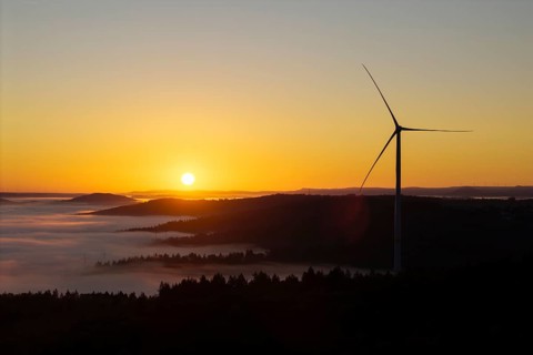 A wind turbine stands over the hills in front of sunrise, near Schorndorf, Rems-Murr district,