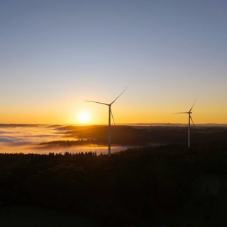 Two wind turbines overlook the foggy forest landscape at sunrise, near Schorndorf, Rems-Murr
