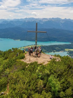 People standing around a summit cross with a view of the surrounding landscape, Herzogstand summit,