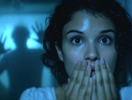 A woman gripped by fear, behind her an eerie silhouette of a shadow, symbolic image for anxiety