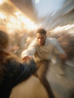 A man gets into a fighting stance, surrounded by dynamic movement and a background filled with