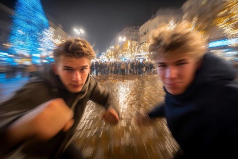 Two men in fighting pose on a rainy street at night, surrounded by lights, symbolic image for