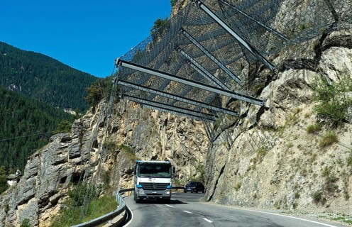 Motor vehicles travelling under safety nets on the rockfall-prone road Les Pontis, Val d'Anniviers,