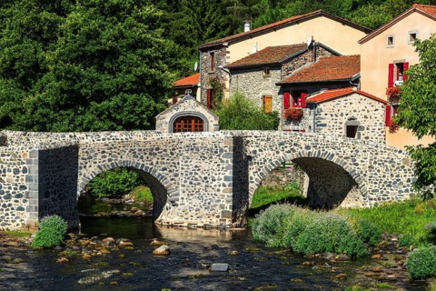 Stone bridge over the Pavin couze river flowing through the village of Saurier, Puy de Dome.