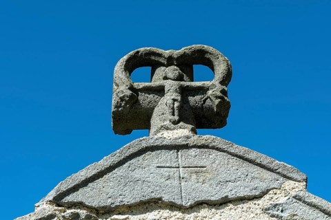 Stone cross on the bridge over the Pavin couze river flowing through the village of Saurier, Puy de