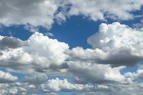 Many white altocumulus clouds cluster clouds under a bright blue sky can be seen through gaps in