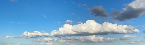 Panoramic photo of extended long wide stratocumulus white cloud cumulus clouds in front of bright
