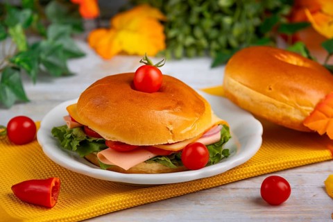 An autumnally decorated table with a filled bagel and colourful leaves