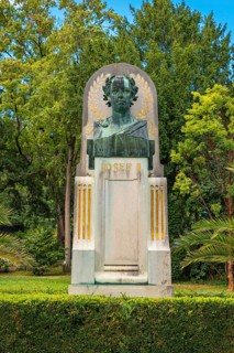 Bust of Joseph II on a monument, embedded in lush greenery and trees, spa garden Baden, Lower